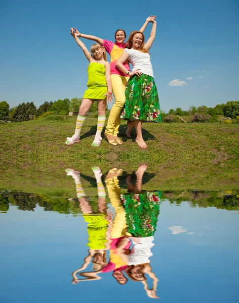 Mãe e duas filhas pulando no prado verde — Fotografia de Stock