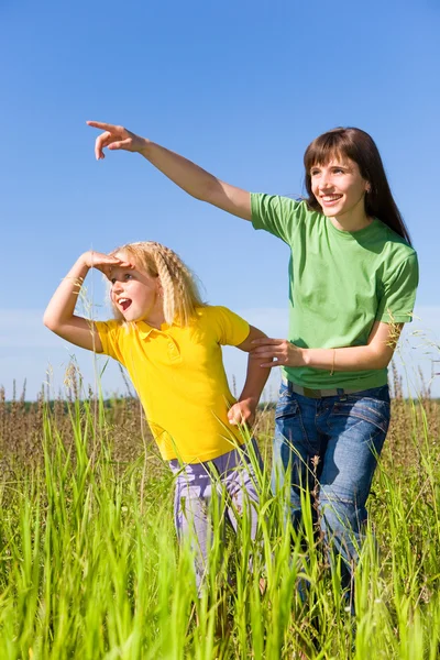 Gelukkige vrouw en meisje op veld. meisje verrast iets. — Stockfoto