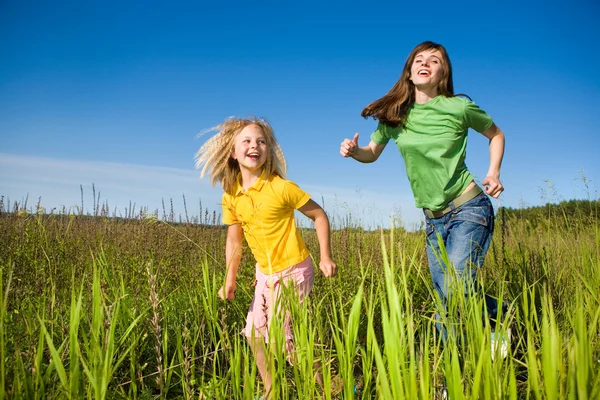 Mutlu anne ve kızı sahada koşmak — Stok fotoğraf