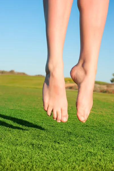Zbliżenie stóp skoków na zielone pole kobieta — Zdjęcie stockowe