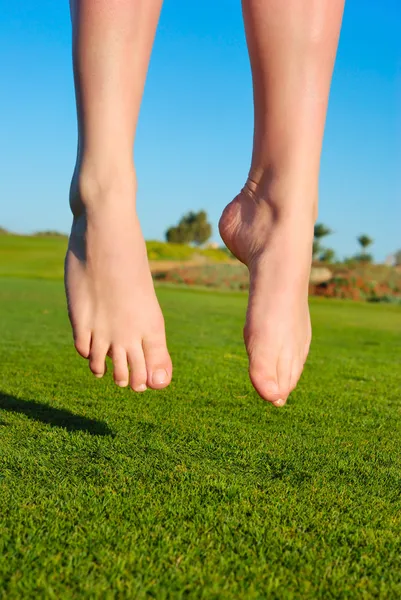 Gros plan de pieds de saut sur vert champ femme — Photo