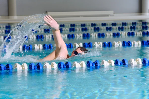 Человек плавает, используя инсульт в крытом бассейне — стоковое фото