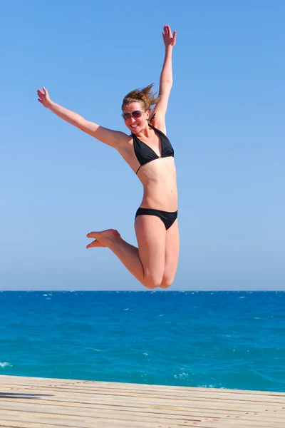 Mooie vrouw springt in de buurt van de zee — Stockfoto