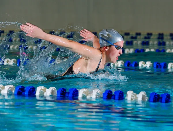 Nő úszik a pillangóúszás a beltéri — Stock Fotó
