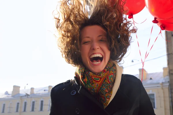 Donna ridente con palloncini rossi sulla città primaverile — Foto Stock