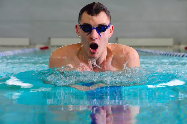 Чоловік плаває за допомогою грудного удару в критому басейні — стокове фото