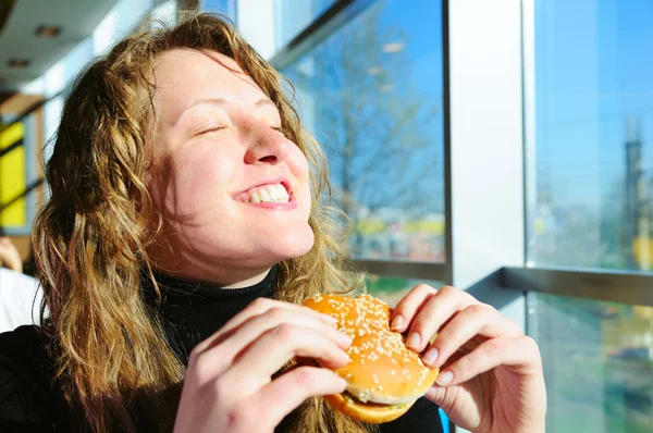 Mujer muy feliz está comiendo hamburguesa con queso —  Fotos de Stock