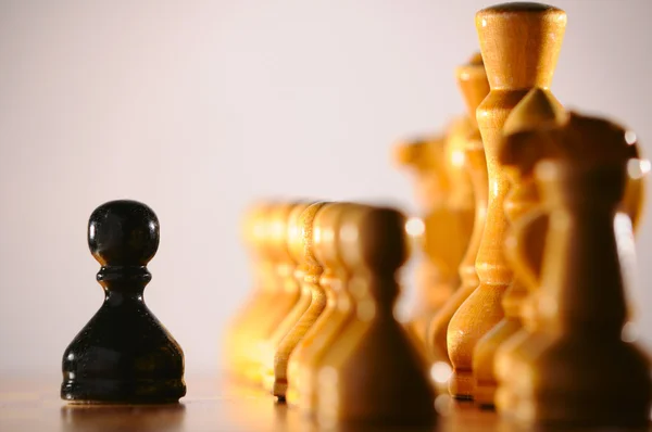 Черная пешка против армии белых шахмат — стоковое фото