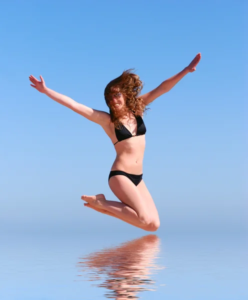 Young beautiful woman jumps against the sea — Stock Photo, Image