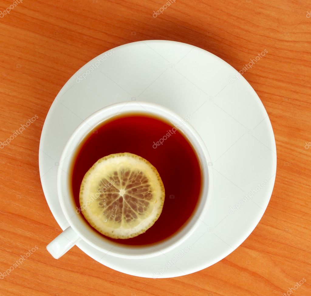 Tea cup with lemon on wooden table from above