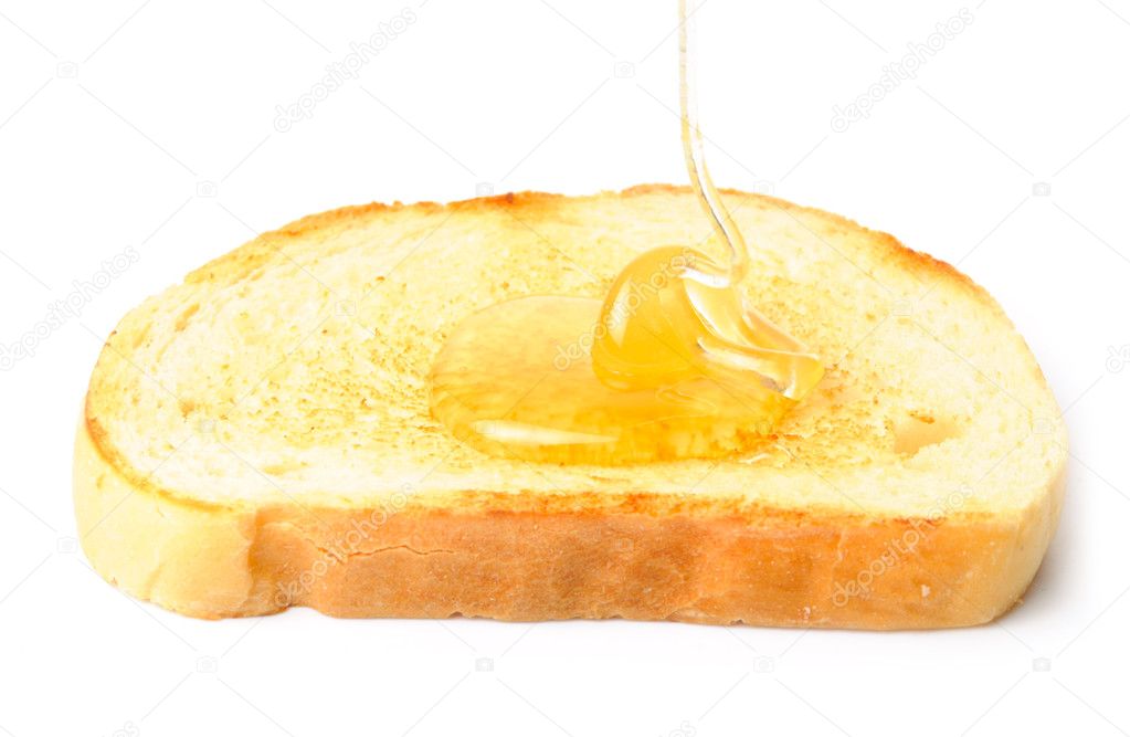 Honey pouring down to white bread. isolated on w
