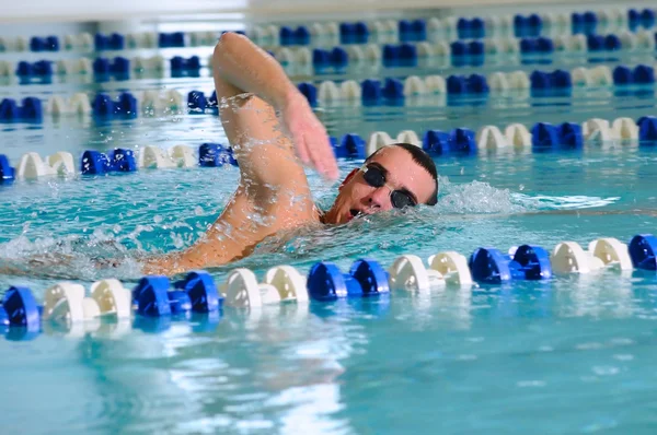 Muž plave pomocí lezení mrtvice v krytém bazénu — Stock fotografie