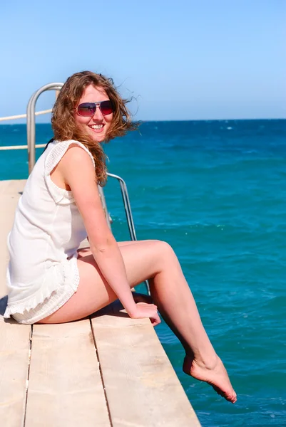 Mooie vrouw alleen zittend op de pier — Stockfoto