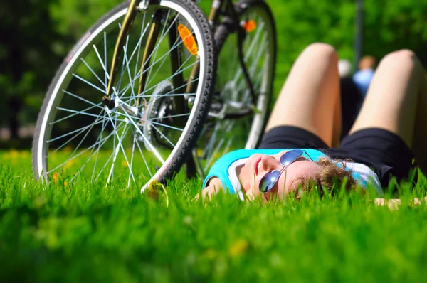 Mulher está deitada perto de sua bicicleta — Fotografia de Stock