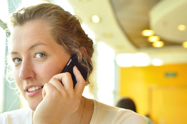 Young woman is talking phone and looking at camera — Stock Photo, Image