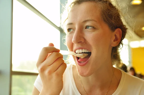 Mulher está comendo sobremesa usando colher no café — Fotografia de Stock