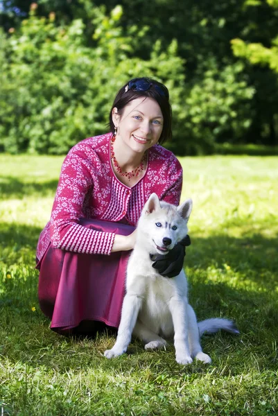 Женщина и щенячий сибирский хаски — стоковое фото