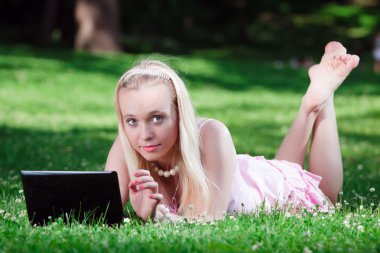 Park yerinde dizüstü bilgisayar kullanan genç bir kadın