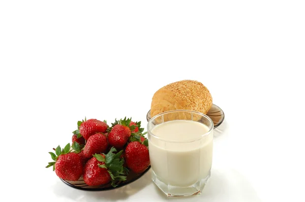 Un vaso de leche con fresas maduras y un panecillo — Foto de Stock