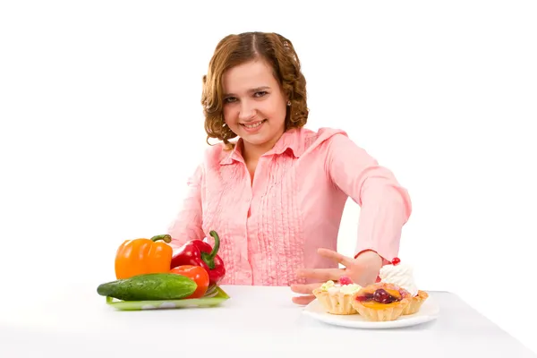 Frau wählt Kuchen und Gemüse — Stockfoto