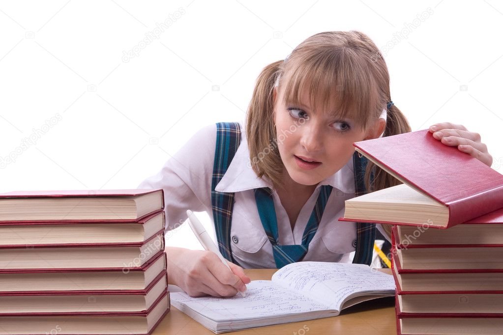 Schoolgirl is sitting and watching furtively textbook.