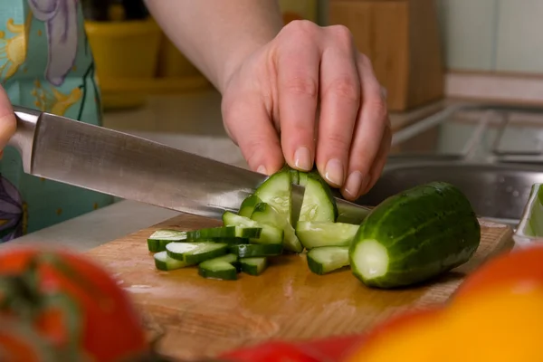 Handen van cook snijden komkommer. — Stockfoto