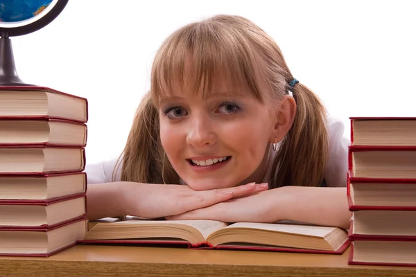 Schoolgirl is sitting on the stack of book and reading. Royalty Free Stock Images