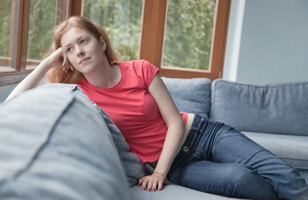 Mujer joven en un sofá — Foto de Stock