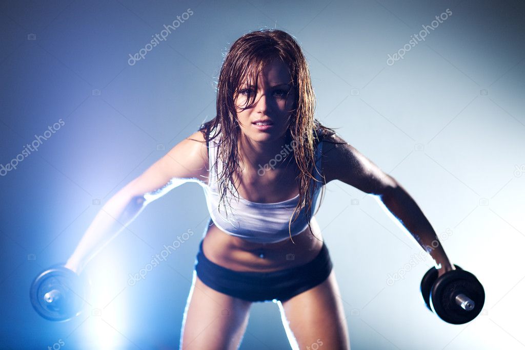 Young strong sexy woman with dumbbells