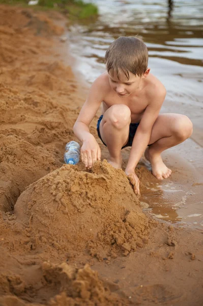 The boy builds on sand — Stock Photo, Image