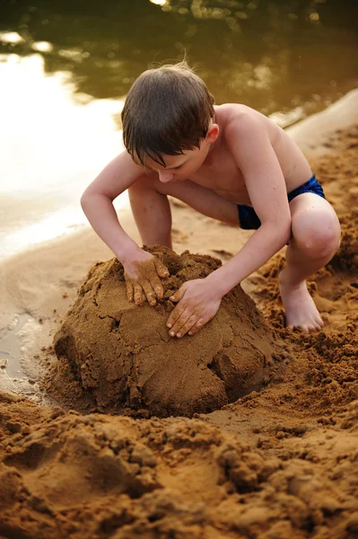 Le garçon construit sur le sable — Photo