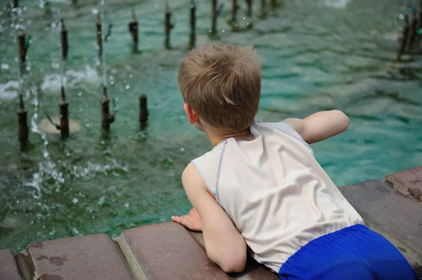 De jongen op rollen bij een fontein — Stockfoto