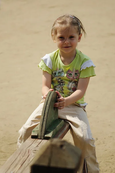 Das Mädchen spielt auf einem Kinderspielplatz — Stockfoto