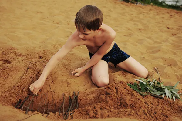 Мальчик строит на песке Стоковое Изображение