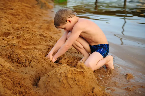 Хлопчик будує на піску Стокове Зображення
