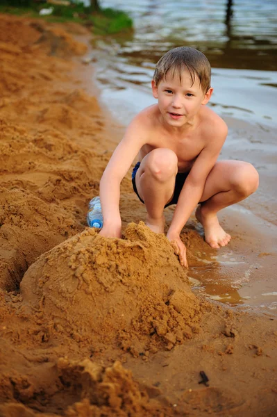 Хлопчик будує на піску Стокове Фото