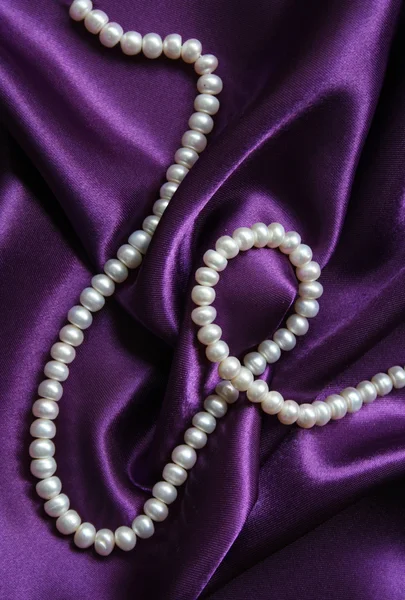 Perle bianche su uno sfondo di seta lilla — Foto Stock