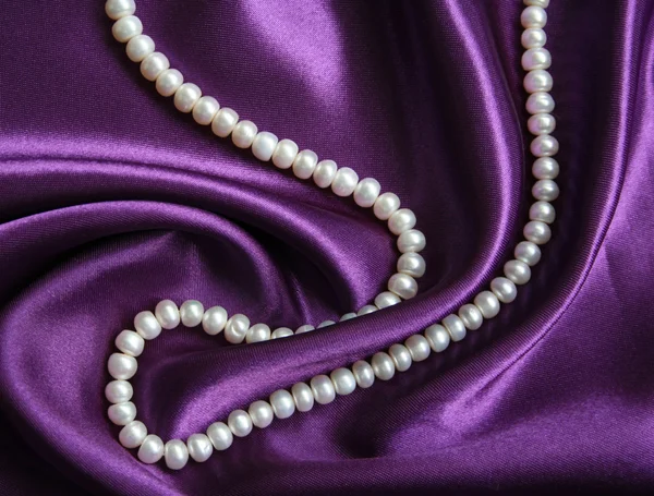 Vita pärlor på en lila siden — Stockfoto