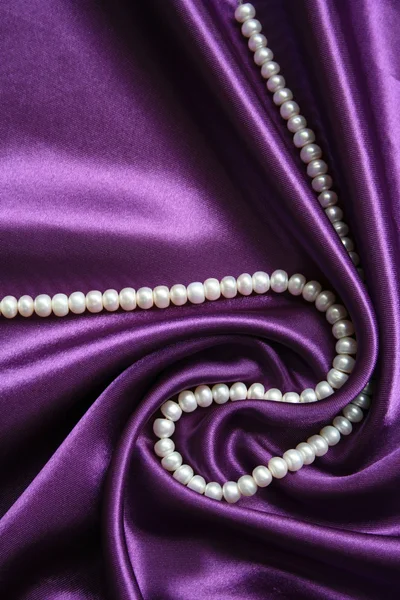 Perle bianche su uno sfondo di seta lilla — Foto Stock