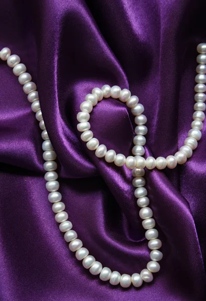 Białe perły na jedwabiu liliowy — Zdjęcie stockowe