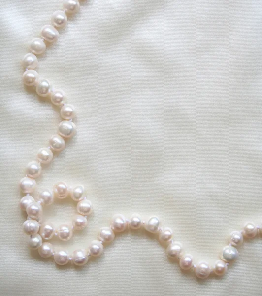 Perlas blancas sobre la seda blanca — Foto de Stock