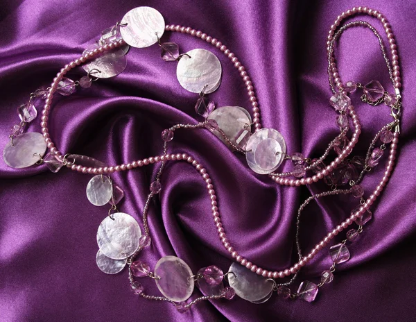 Perle lilla su una seta lilla — Foto Stock