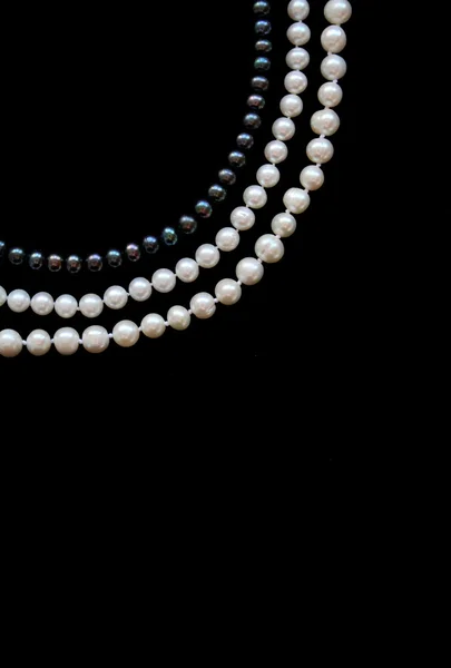 Weiße und schwarze Perlen auf schwarzer Seide — Stockfoto