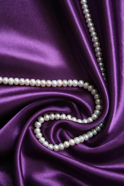 Perlas blancas sobre seda lila —  Fotos de Stock