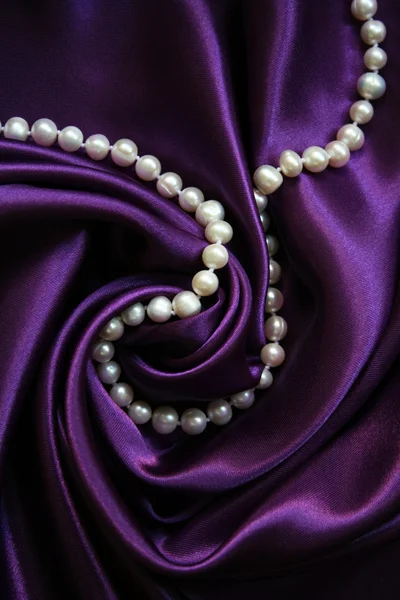Białe perły na jedwabiu liliowy — Zdjęcie stockowe