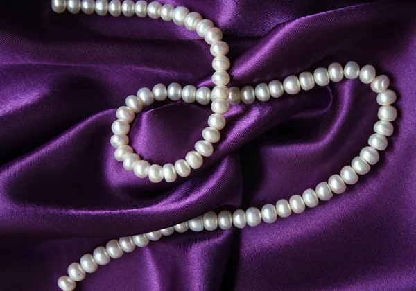 Witte parels op een Lila zijde — Stockfoto
