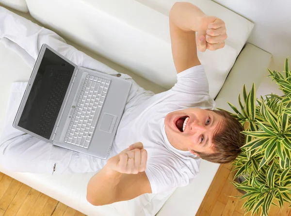 快乐的年轻男子坐在沙发上，使用笔记本电脑的顶视图 — 图库照片
