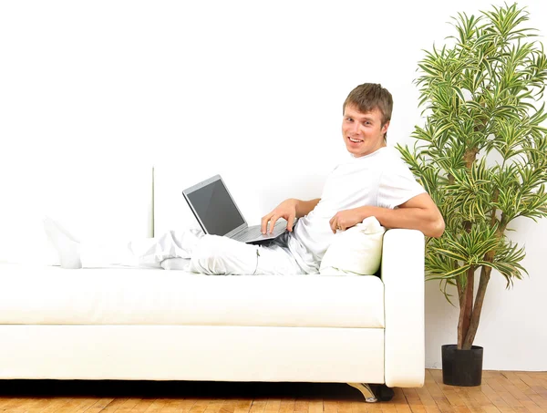 Gülümseyen genç adam evde dizüstü bilgisayar üzerinde çalışan — Stok fotoğraf