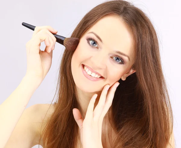 Atractiva mujer joven aplicando colorete — Foto de Stock