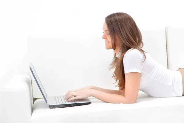 Smiling woman lying on sofa with laptop. — Stock Photo, Image